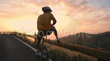 一位戴着头盔和运动器材的职业自行车手站在山的边缘，可以看到美丽的景色。